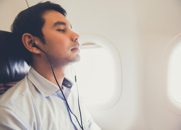 sleeping-male-passenger-wearing-headsets-listening