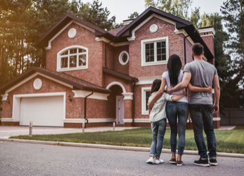 happy-family-standing-near-their-home